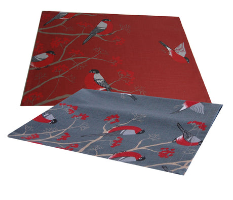 Ein rotes und ein graues rechteckiges Platzset auf einem weissen Hintergrund. Die Platzsets sind mit rot-grau-schwarzen Voegeln, die auf Zweigen mit roten Beeren sitzen, bedruckt.
