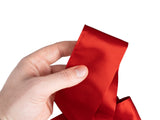 Augenbinde aus Glanzsatin in karmin-rot in der Hand – glatter, glänzender Satin