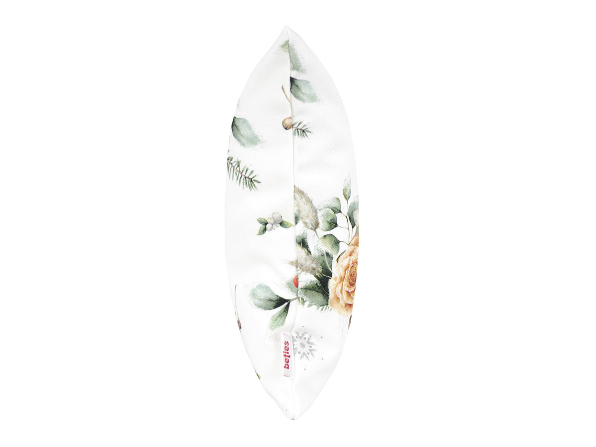 Weisse Kissenhuelle ca. 25x35 cm – Winterdeko mit orangen, gefrosteten Rosen, Kieferzapfen und Zweigen im Alloverdruck. Ansicht von der Seite mit dem beties Label – 100% Baumwolle – Aus der beties Magie des Winters "Frost-Rose" Kollektion.